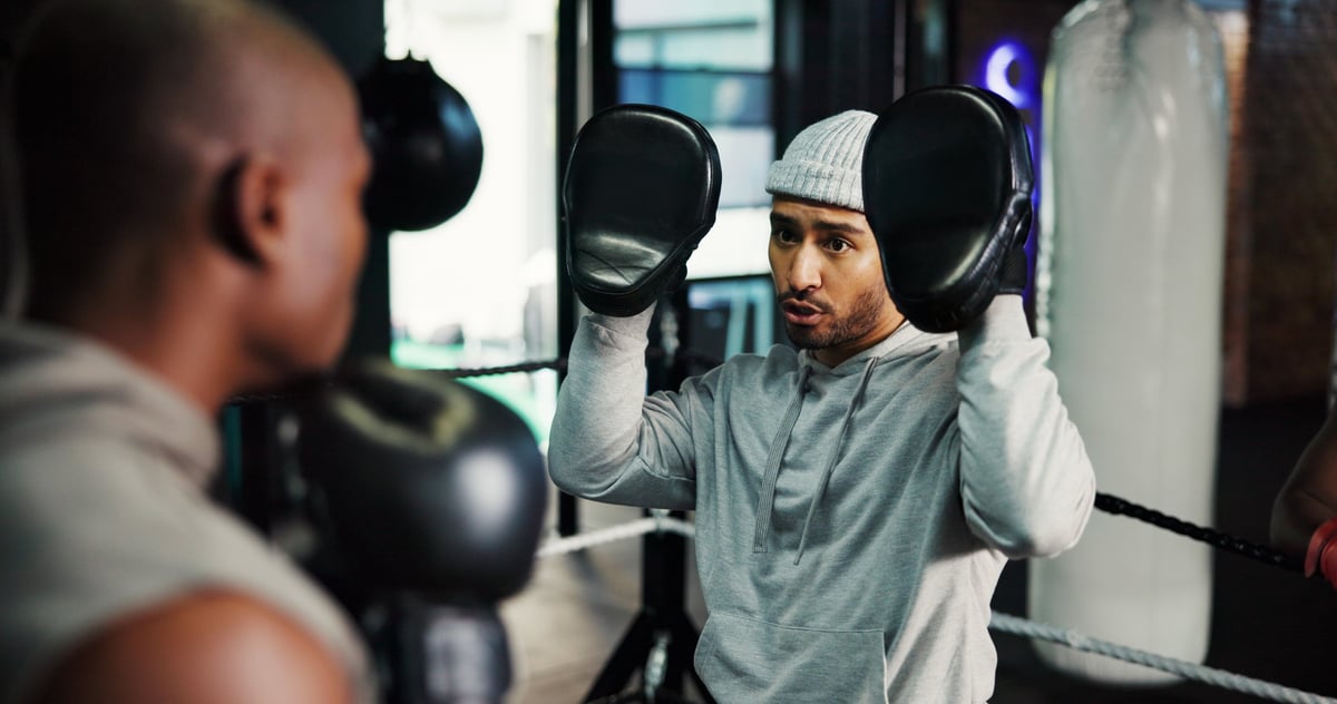 Man, boxing and coach for punch at gym for power, challenge or martial arts training