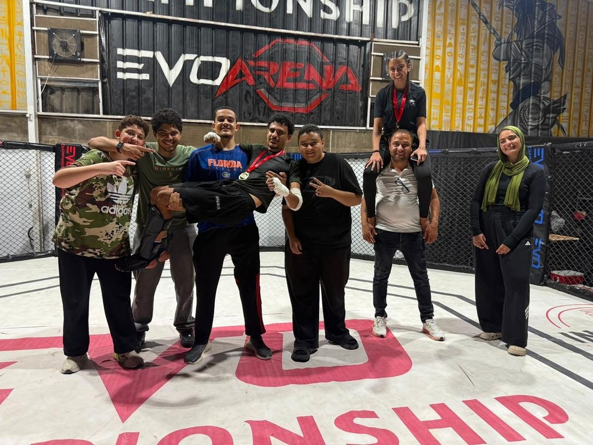 Group of people posing together inside an EVO Arena sports facility with championship signage visible in background