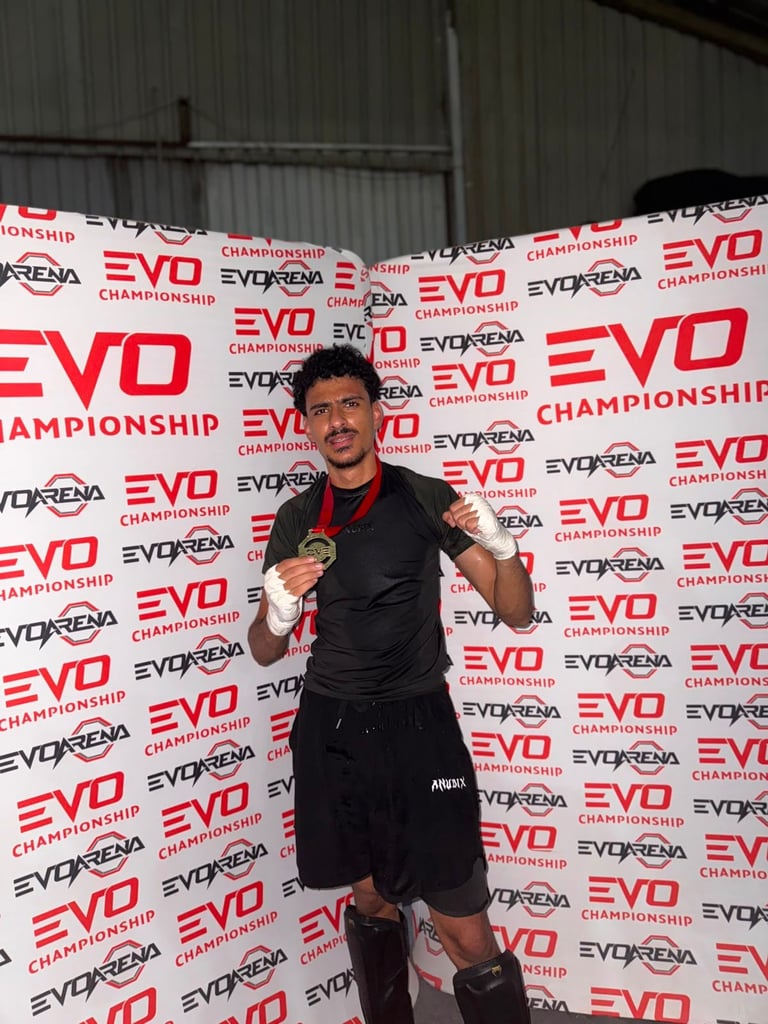 Shirtless fighter in boxing pose at EVO Championship event with branded backdrop
